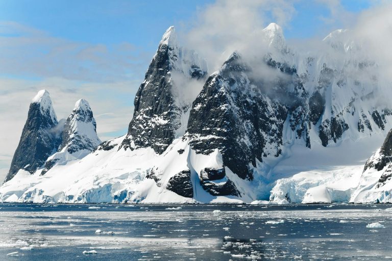 Majestic snowy peaks rise over icy Antarctic waters, showcasing untouched nature.