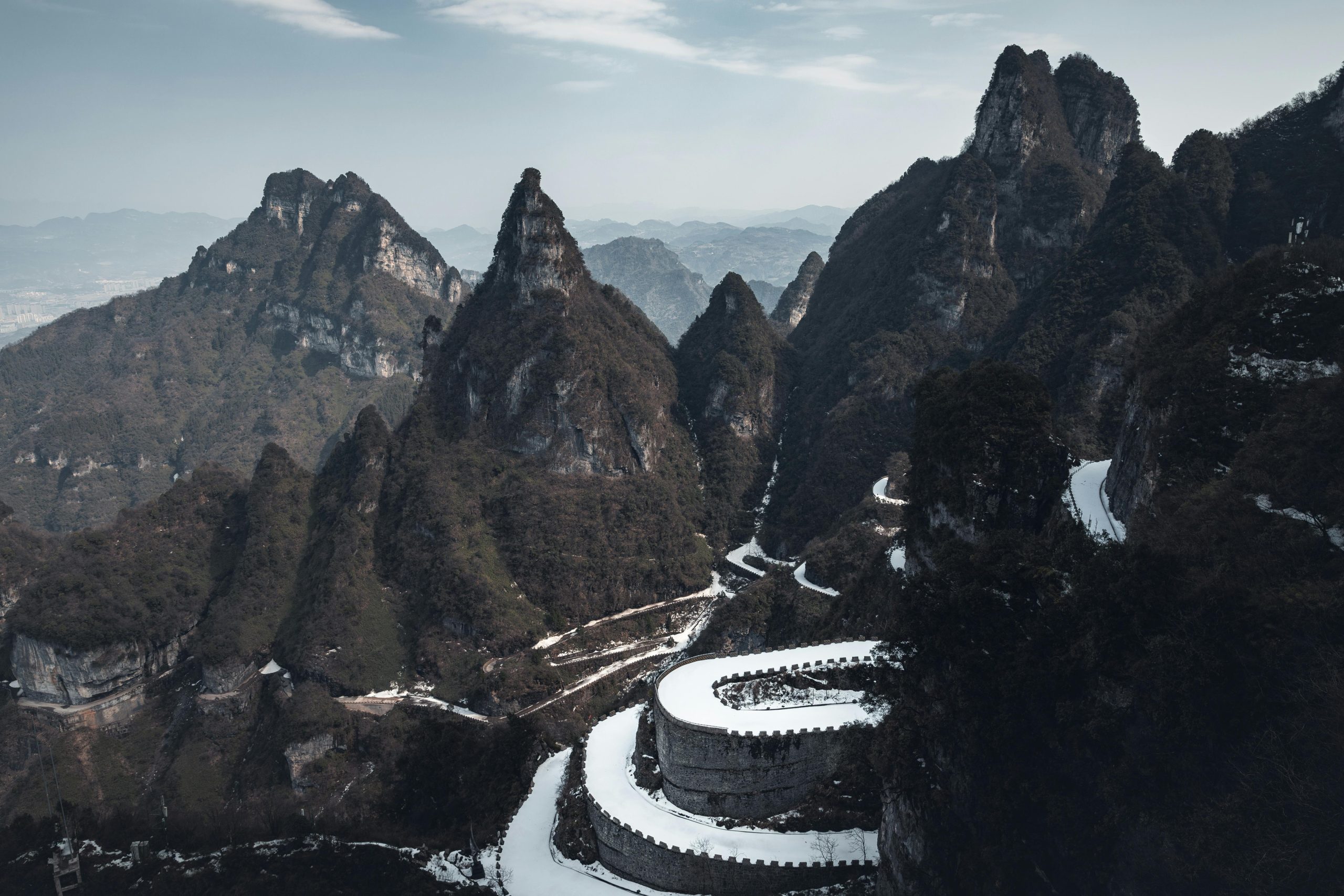 Aerial view of Zhangjiajie's dramatic mountainous landscape and serpentine road.